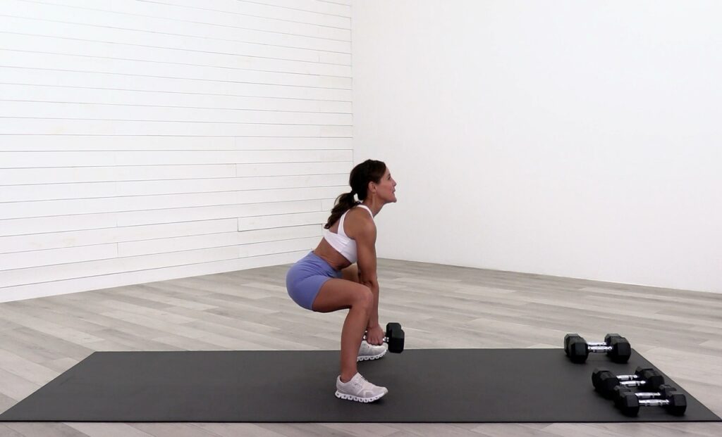 Woman performing a squat using heavy dumbbells for bone and spine health perimenopause and post menopause